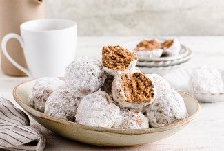 A plate of horchata polvorones coated in sugar next to a hot drink